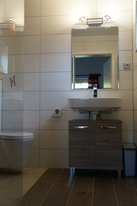 Modern bathroom at Camping Altschmiede - Lodges Rijnland-Palts, featuring a mirror, sink, and toilet.