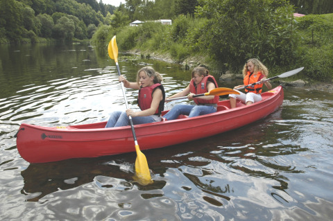 Tre persone che remano in una canoa rossa vicino a Camping Altschmiede - Lodges Rijnland-Palts nella natura.