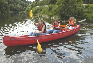 Trois personnes pagayant dans un canoë rouge près du Camping Altschmiede - Lodges Rijnland-Palts en nature.