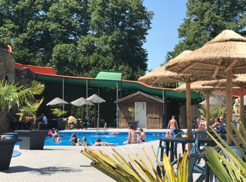 Piscina all'aperto e scivolo d'acqua al Vakantiepark De Oude Molen Safaritent Gelderland con persone che nuotano.