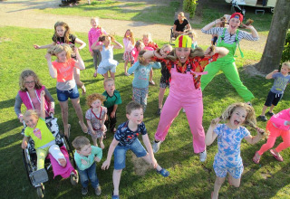 Niños y adultos juegan al aire libre bajo el sol en Vakantiepark De Oude Molen - Safaritent Gelderland, glamping.