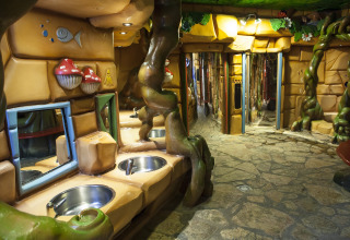 Baño temático de bosque con ramas, setas de colores y lavabos en Vakantiepark De Oude Molen, Gelderland.