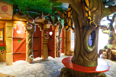 Bunte, thematische Indoor-Spielplatz mit Bäumen, Schlangen und roten Türen in Safaritent Gelderland.
