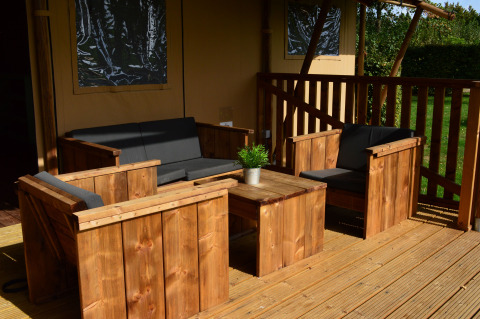 Salotto all'aperto in legno con cuscini neri al Vakantiepark De Oude Molen - Safaritent Gelderland.