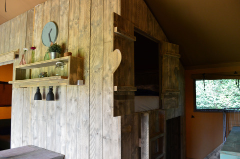 Cozy interior of a glamping cabin at Safaritent Gelderland with wooden walls and decorative shelves.