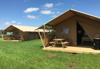 Alojamiento glamping con bancos de picnic y área verde en Glamping - aan de Vleterbeke en un día soleado.