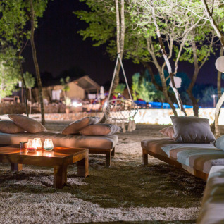 Zona lounge exterior de noche en Camping Nono Ban - Safaritenten Brac con sofás y velas encendidas.