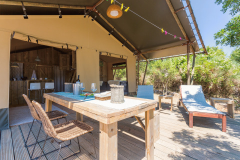 Terrasse extérieure avec table à manger et transats au Camping Nono Ban - Safaritenten Brac glamping.