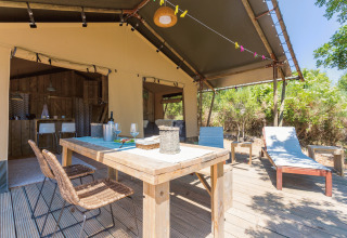 Terrasse extérieure avec table à manger et transats au Camping Nono Ban - Safaritenten Brac glamping.
