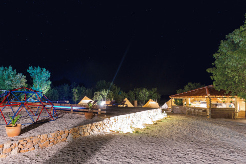 Camping Nono Ban - Safaritenten Brac glampingterrein 's nachts met verlichte tenten en speelhoek.