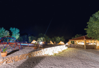 Camping Nono Ban - Safaritenten Brac di notte con tende illuminate, area giochi e bar all'aperto.