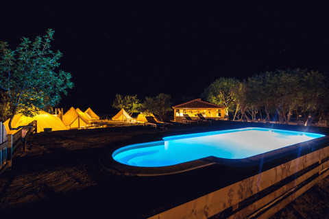 Glamping al Camping Nono Ban - Safaritenten Brac con piscina illuminata, tende e alberi di notte.