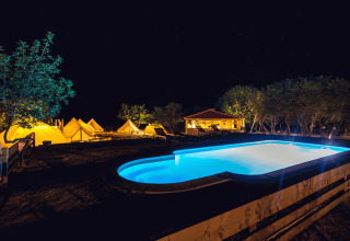 Glamping en Camping Nono Ban - Safaritenten Brac con piscina iluminada, tiendas y árboles de noche.