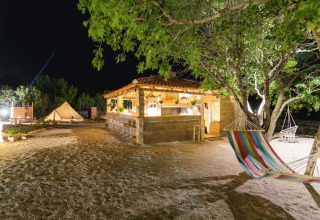 Camping de glamping Camping Nono Ban - Safaritenten Brac de noche con tienda, hamaca y luces exteriores.