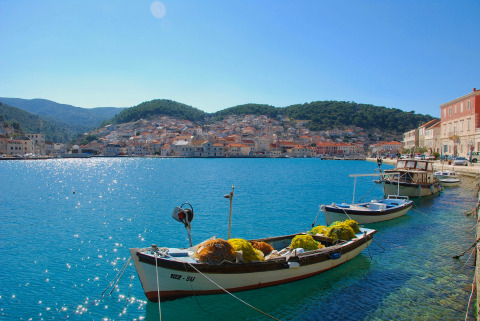 Boats docked on clear blue water near Camping Nono Ban - Safaritenten Brac with a scenic town behind.