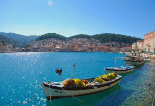 Boats docked on clear blue water near Camping Nono Ban - Safaritenten Brac with a scenic town behind.