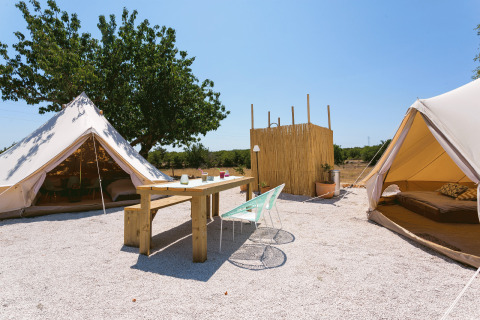 Buiten glamping bij Camping Nono Ban - Safaritenten Brac met safaritenten, houten tafel en gezellige zithoek.