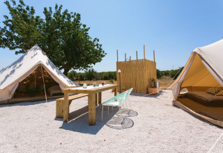 Glamping-Platz Camping Nono Ban - Safaritenten Brac mit Safarizelten, Holztisch und Außenbereich bei Sonne.