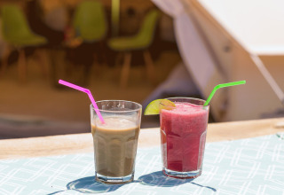 Twee verfrissende drankjes met rietjes op een tafel voor een safaritent bij Camping Nono Ban - Safaritenten Brac.