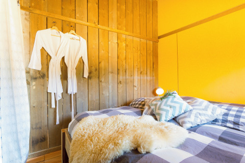 Comfortable glamping room at Camping Nono Ban with double bed, bathrobes, stylish pillows, and warm decor.