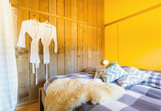 Chambre de glamping confortable au Camping Nono Ban avec lit double, peignoirs et décoration chaleureuse.