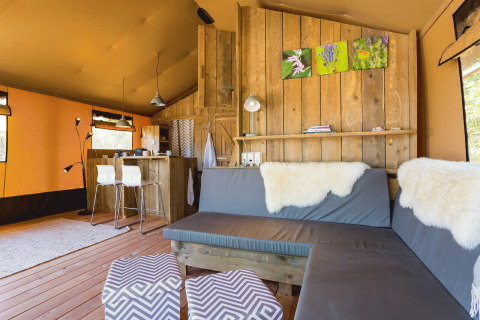 Interieur van een luxe safaritent op Camping Nono Ban met moderne zetels en warme houtaccenten.