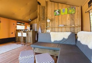 Interior de una lujosa tienda safari en Camping Nono Ban, con muebles modernos y toques de madera.