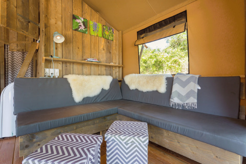 Inviting glamping lounge with a corner sofa, wood walls, and window at Camping Nono Ban - Safaritenten Brac.