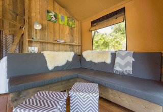 Sfeervolle glamping zithoek met hoekbank en houten wand bij Camping Nono Ban - Safaritenten Brac.