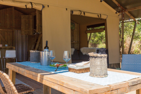 Buitentafel met wijn en glazen bij een luxe safaritent op Camping Nono Ban - Safaritenten Brac.