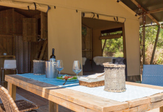 Mesa al aire libre con vino y copas junto a una tienda de lujo en Camping Nono Ban - Safaritenten Brac.