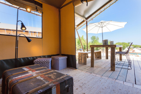 Interior de glamping elegante con muebles de madera y terraza exterior en Camping Nono Ban - Safaritenten Brac.