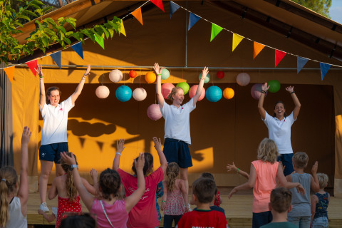 Des enfants participent à une animation de scène au Trasimeno Glamping Resort, des animateurs les guident.