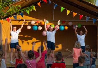 Kinder nehmen an Animation und Spielen teil mit Betreuern auf der Bühne bei Trasimeno Glamping Resort.