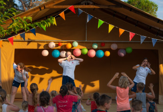 Children join an activity with instructors on a decorated stage at Trasimeno Glamping Resort in Umbria.