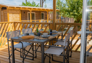 Terrasse am Trasimeno Glamping Resort mit gedecktem Tisch zum Frühstück, umgeben von Natur und Ferienhäusern.