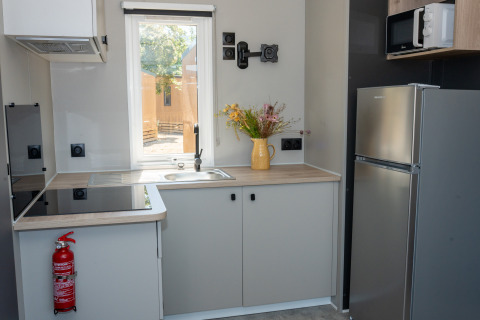 Cocina moderna en Trasimeno Glamping Resort - Cottages Umbrië con nevera, microondas y ventana luminosa.