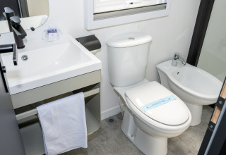 Salle de bain moderne avec lavabo, robinet noir, toilettes et bidet au Trasimeno Glamping Resort en Ombrie.