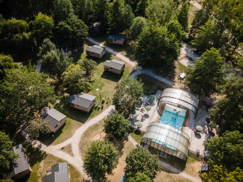 Vue aérienne de Huttopia Les Châteaux Glamping Val de Loire avec cabanes, piscine et arbres verdoyants.
