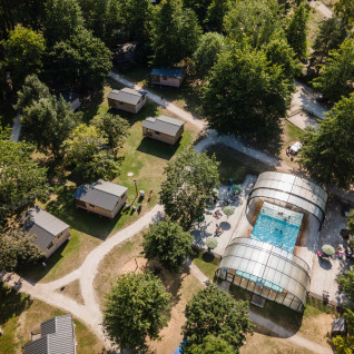 Vista aérea de Huttopia Les Chateaux Glamping Val de Loire con cabañas, piscina y árboles frondosos.