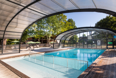 Overdekt zwembad met houten terras en ligstoelen op Huttopia Les Chateaux - Glamping Val de Loire camping.