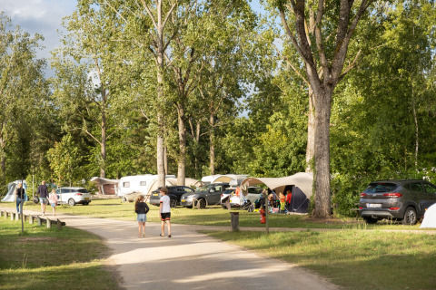 Campingplatz mit Zelten und Wohnwagen zwischen Bäumen bei Huttopia Les Chateaux - Glamping Val de Loire.