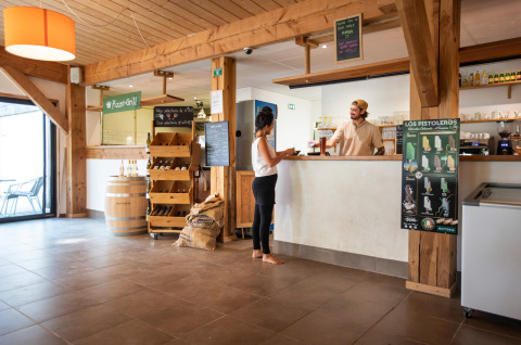 Reception presso Huttopia Les Châteaux - Glamping Val de Loire, ospite parla con staff, arredo in legno.