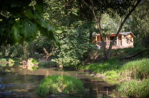 Accogliente cabina in legno vicino al fiume immersa nel verde presso Huttopia Les Chateaux Glamping Val de Loire.