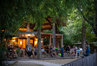 Buiten eetgedeelte bij Huttopia Les Chateaux - Glamping Val de Loire, omringd door groene bomen.