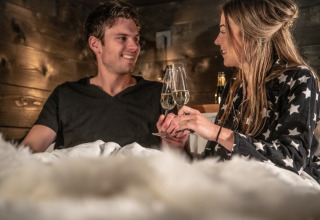 Stel geniet van bubbelwijn in knus glampingverblijf bij Erfgoed Bossem - Sterrenkubussen Twente.