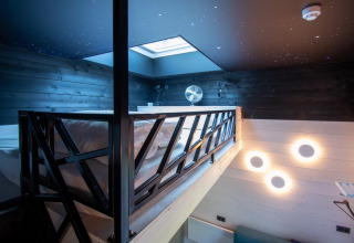 Modern glamping accommodation Sterrenkubussen at Erfgoed Bossem, featuring skylight, loft bed, and stylish lighting.