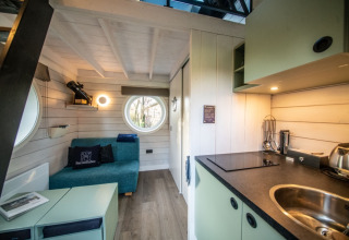 Interno della glamping Erfgoed Bossem - Sterrenkubussen Twente, con divano e angolo cottura moderno.