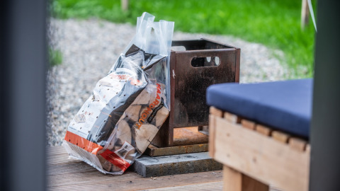 Bag of firewood and metal firepit at glamping accommodation Erfgoed Bossem - Sterrenkubussen Twente.
