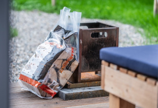 Bag of firewood and metal firepit at glamping accommodation Erfgoed Bossem - Sterrenkubussen Twente.